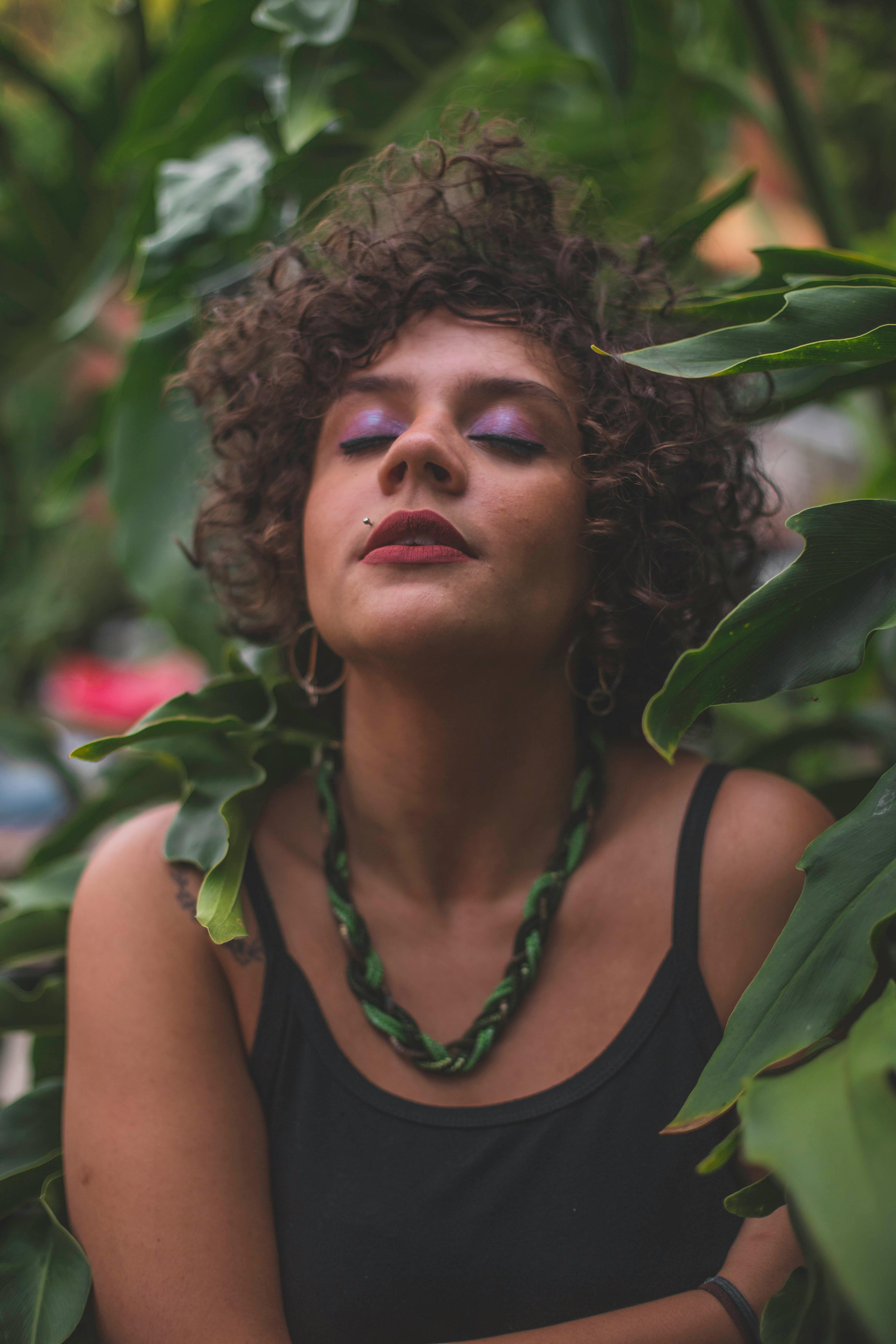 一幅宁静的女性肖像被郁郁葱葱的绿叶环绕，传达着自然的美丽与宁静