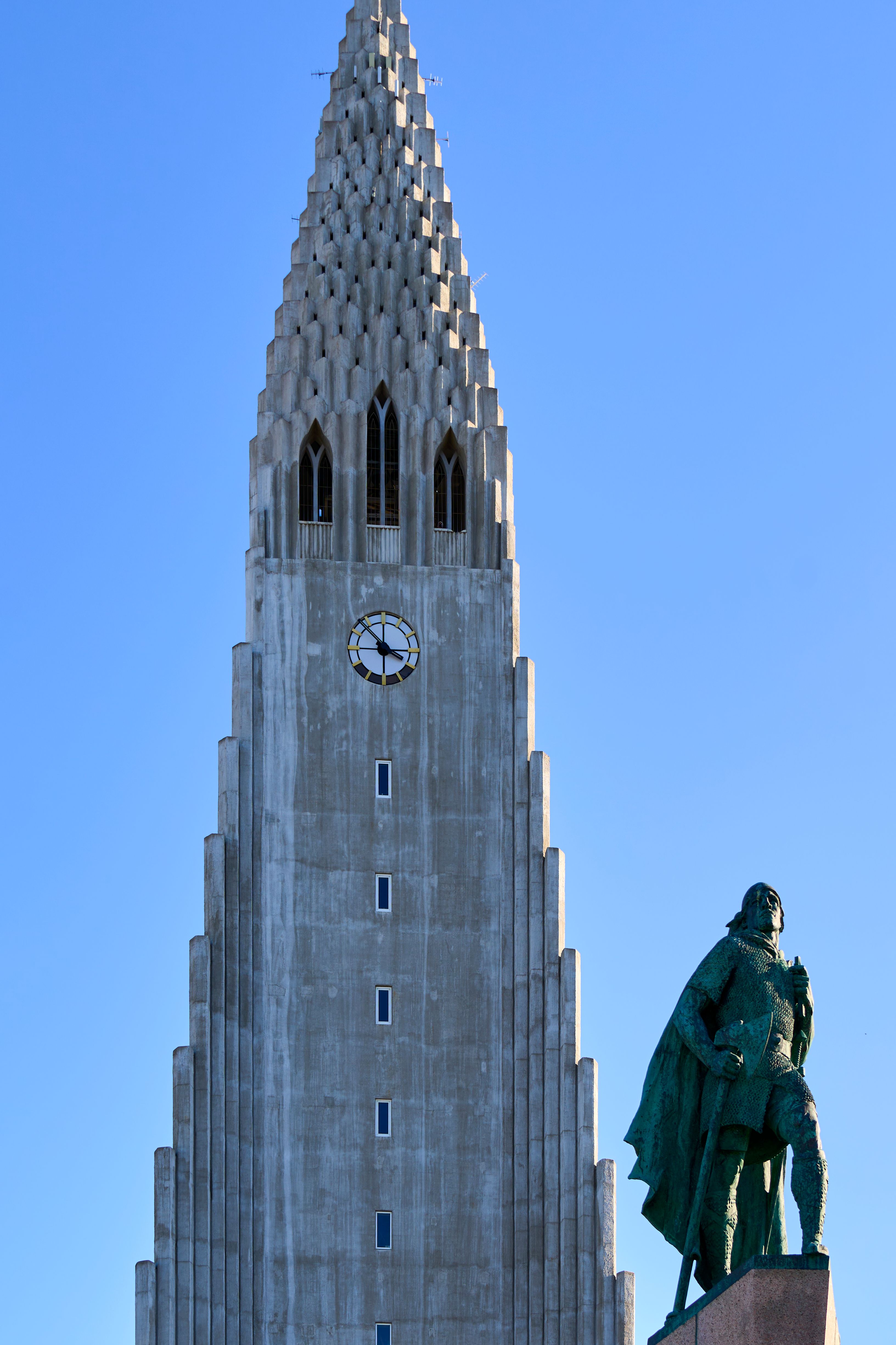 Iconic Hallgrimskirkja church tower and Leif Erikson statue under clear blue skies in Reykjavik, Iceland.
