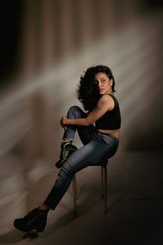 Elegant studio shot of a woman in black top and jeans, showcasing modern fashion.