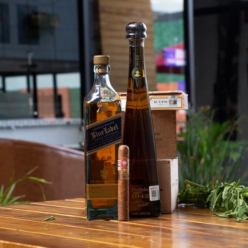 Free Stylish display of liquor bottles and cigar on a wooden table, perfect for nightlife themes. Stock Photo