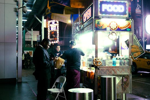 Capture of a bustling city night scene with people gathering around a street food cart.