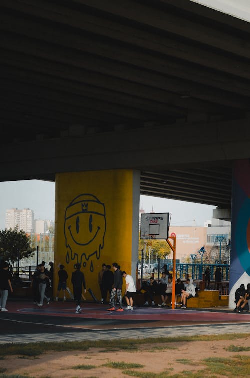 Group of People on a Basketball Court under a Bridge 