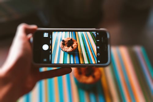 Persona Che Cattura Foto Di Cupcake Al Cioccolato Utilizzando Smartphone