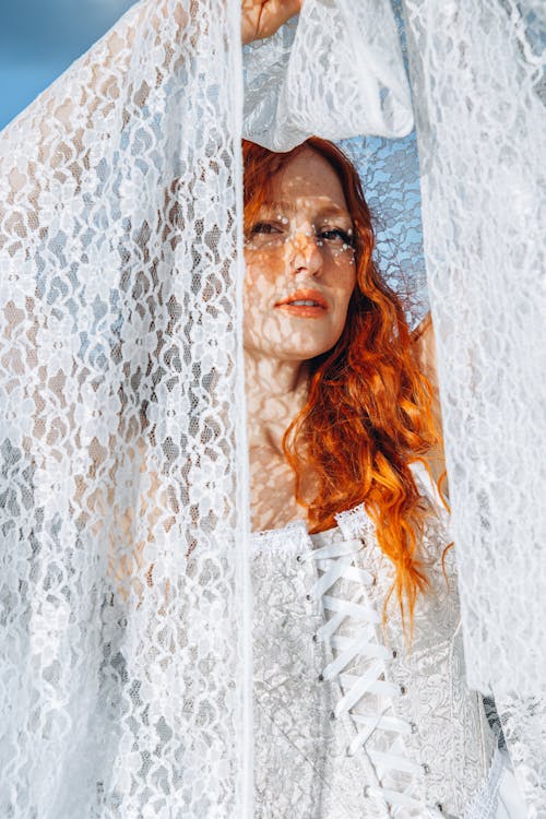 A woman with red hair and white lace dress