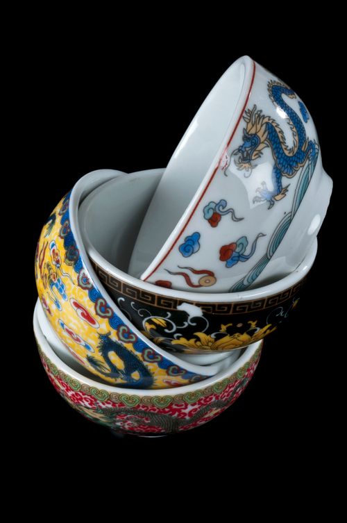 Free Stack of colorful hand-painted porcelain bowls on a black background, showcasing intricate designs. Stock Photo