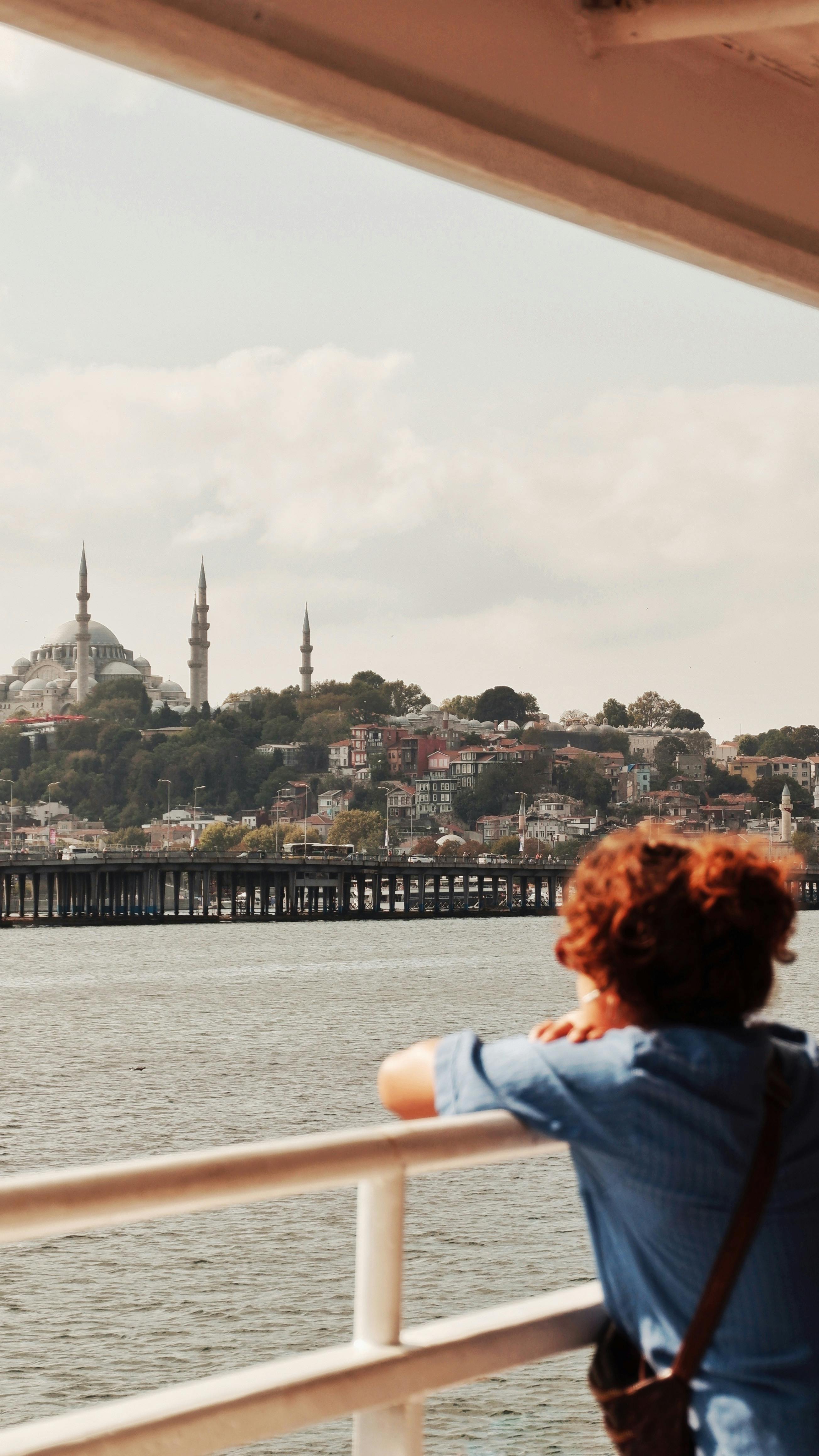 A woman views Istanbul's skyline from a ferry, featuring the Hagia Sophia.