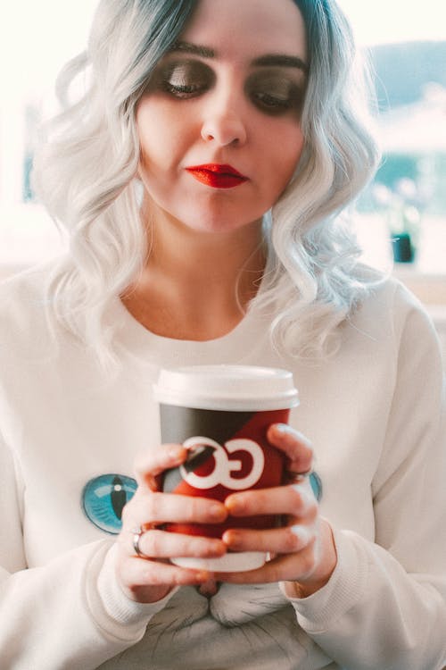 Free женщина носит белый свитер с круглым вырезом и держит одноразовую чашку Go Stock Photo