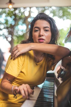 白天，一名穿着黄色衬衫的年轻女子在户外拿着钢琴摆姿势