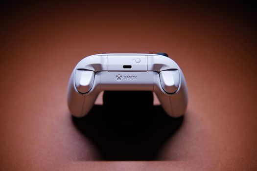 A white Xbox game controller beautifully captured on a light brown background, showcasing modern gaming technology.