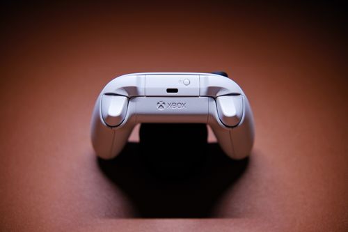 Free A white Xbox game controller beautifully captured on a light brown background, showcasing modern gaming technology. Stock Photo