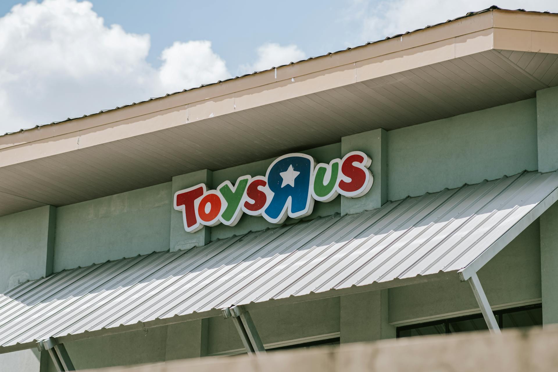 Roof and sign of a Toys R Us store on a sunny day with blue sky.