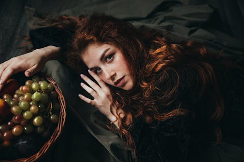 Free Red-haired girl in a green vintage dress with grapes Stock Photo