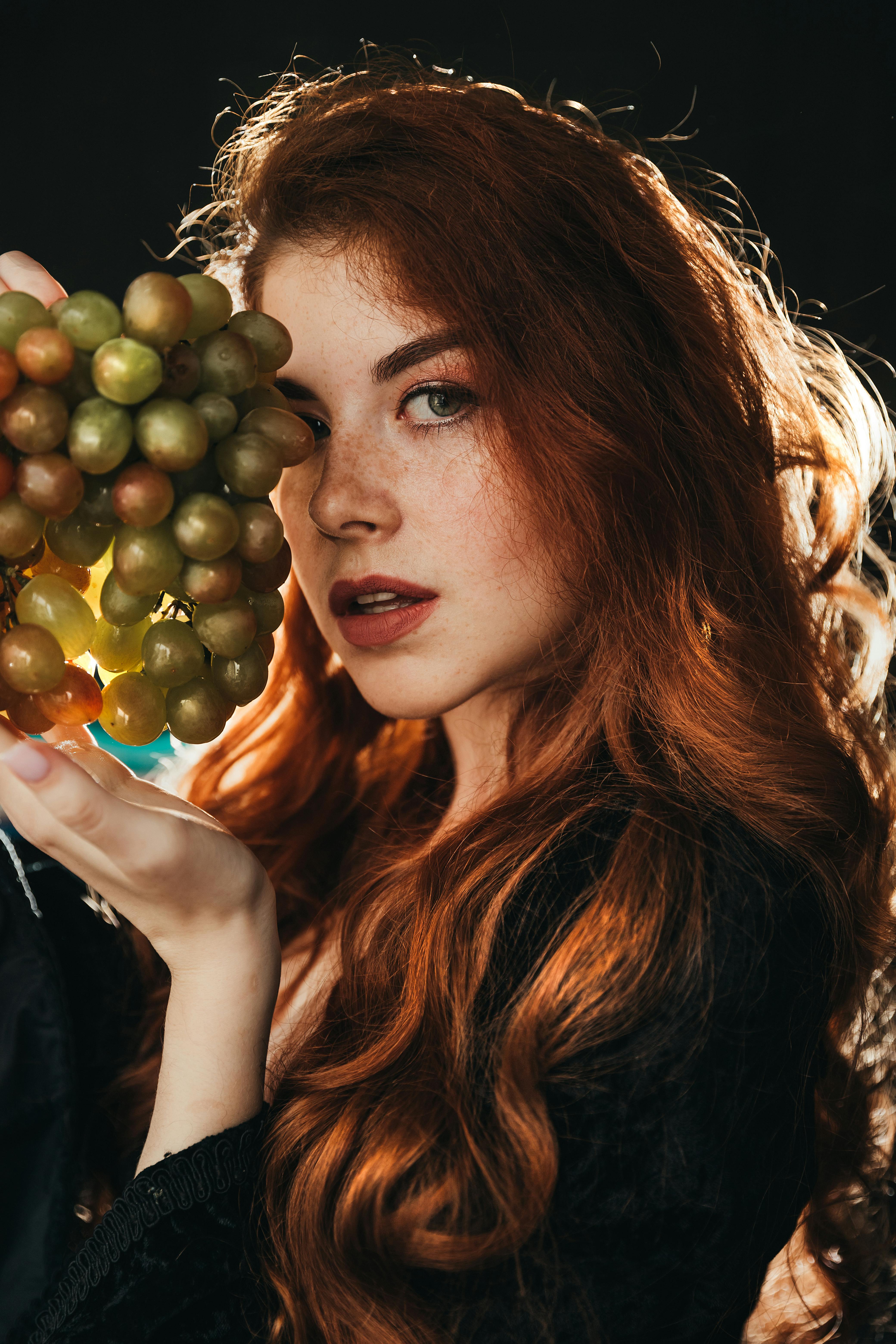 red haired girl in a black vintage dress with grapes