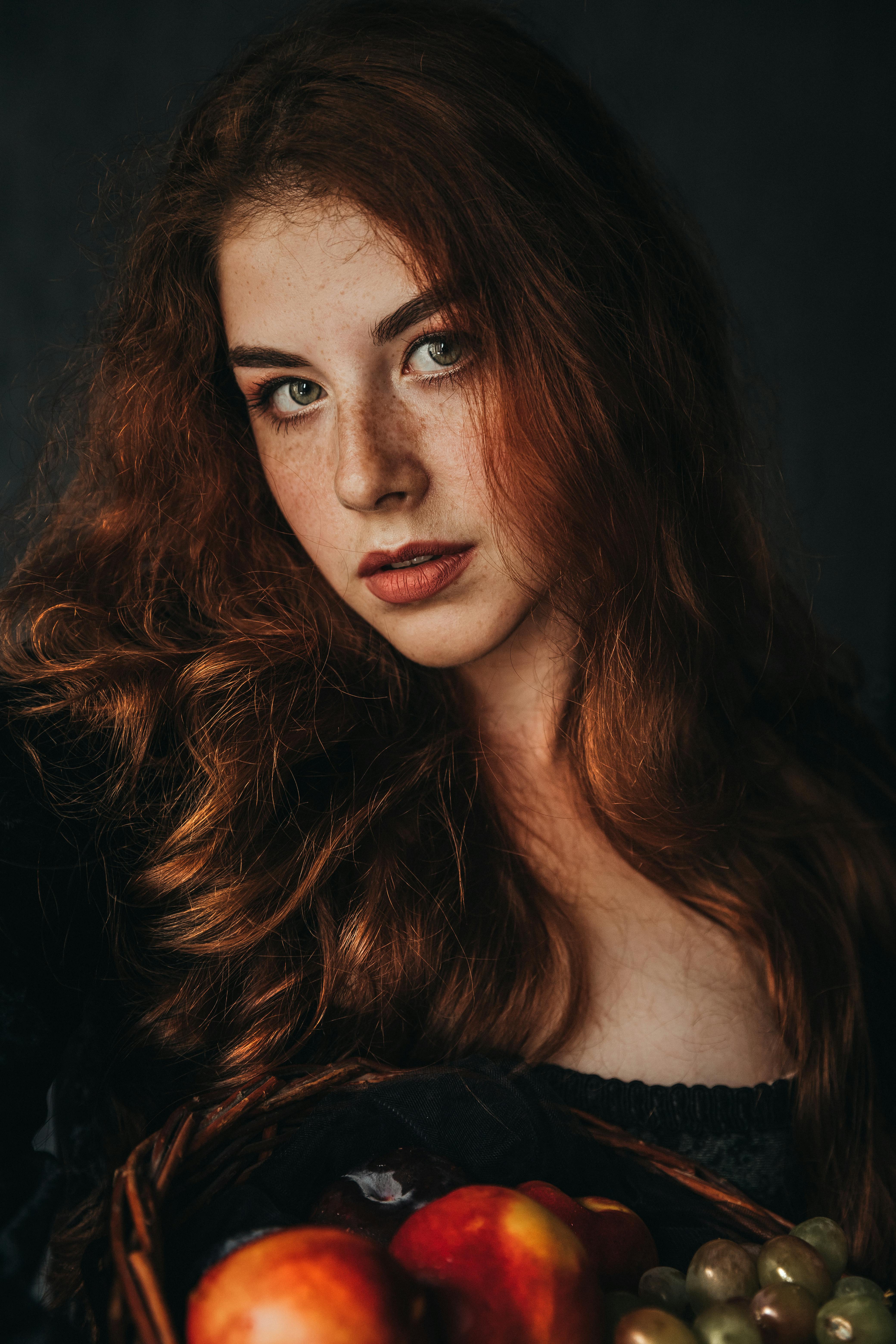 red haired girl in a black vintage dress with grapes