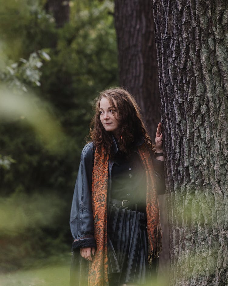 Woman In Coat And Scarf Standing By Trees