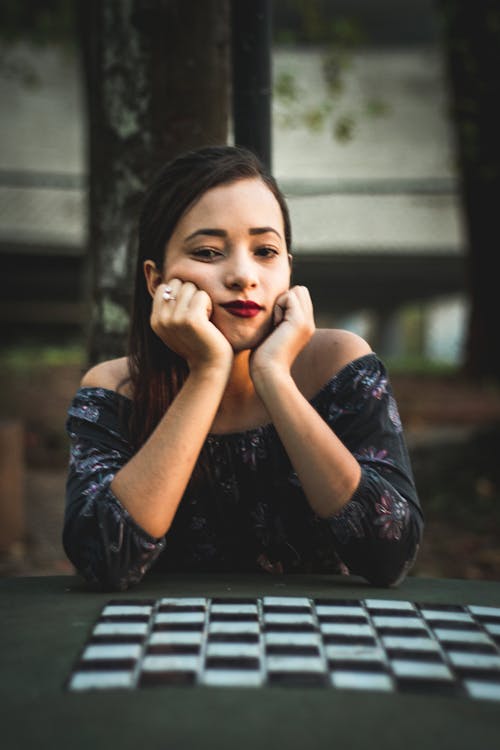 Free Woman Sitting Beside Chess Table With Hands on Chin Stock Photo