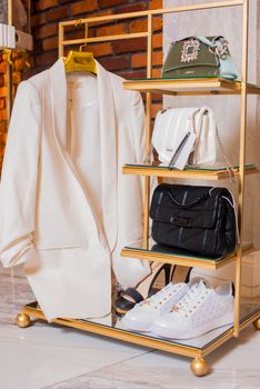 Stylish ensemble showcasing a white jacket, high heels, and luxury handbags.