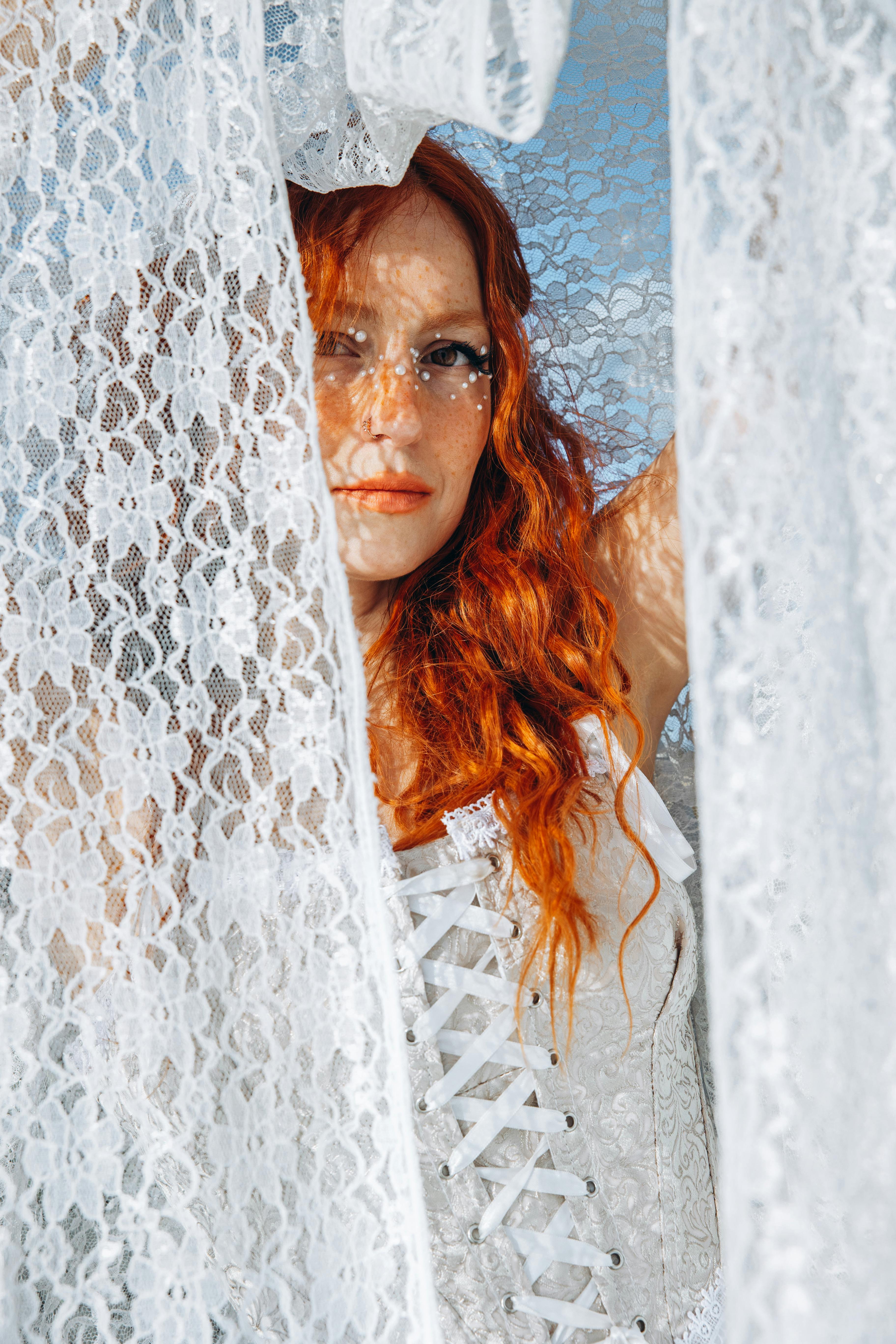 a woman with red hair and long red hair is looking out of a window