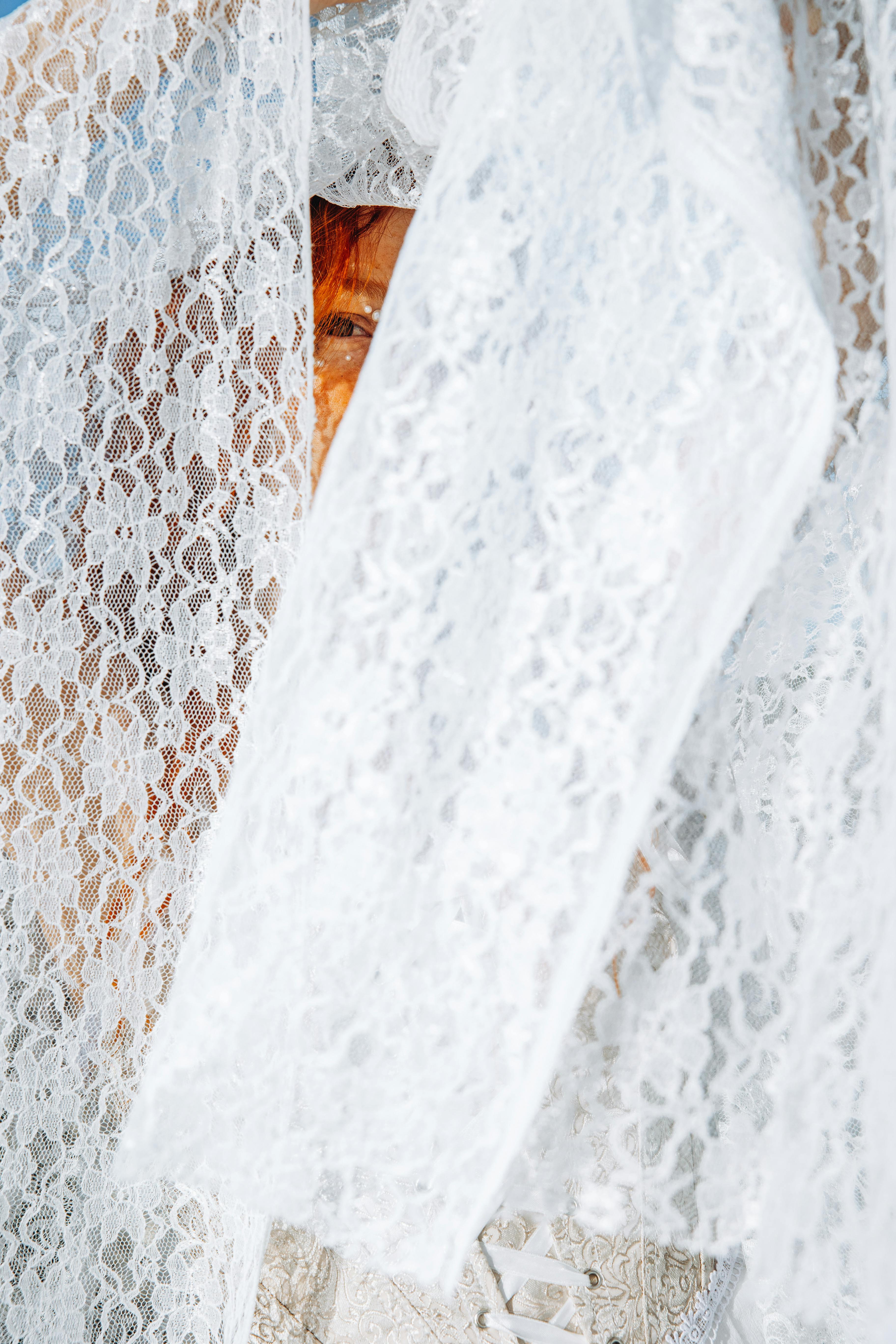 a bride is holding a white lace veil