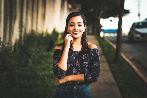 Free Smiling woman in casual wear posing confidently on a sunny city street. Stock Photo