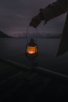 A person holds a glowing lantern at night near Lake Wakatipu, Queenstown, New Zealand.