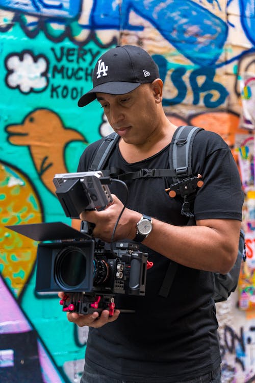 Man Checking his Camera in Front of a Wall with Graffiti