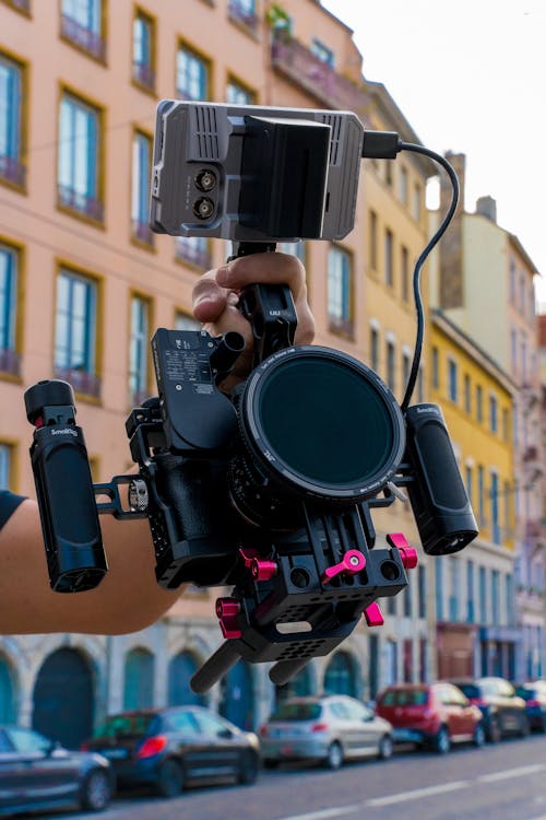 Hand Holding a Camera in the Street of a City