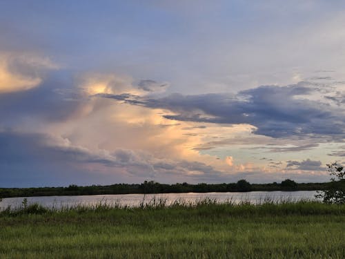 Kostenloses Stock Foto zu gewitterwolken, grünes gras, orange himmel