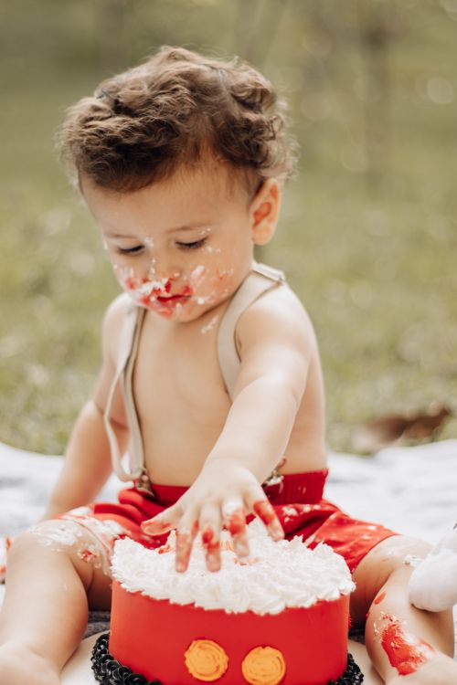 Free Cute toddler indulging in a messy cake smash outdoors, creating joyful memories. Stock Photo
