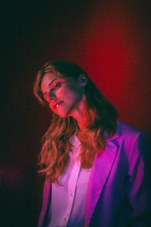 Free Elegant portrait of a woman under dramatic red and purple lighting with a contemplative expression. Stock Photo