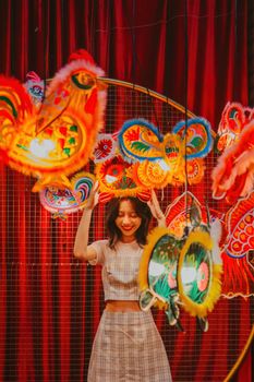 A young woman smiles among colorful festival lanterns, creating a joyful atmosphere.