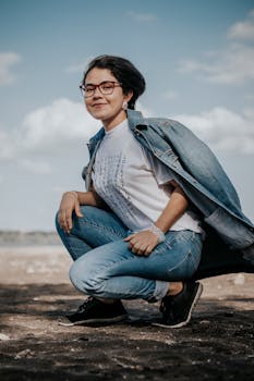 阳光明媚的日子里，一位穿着休闲装的微笑女人蹲在户外，散发着放松和自信