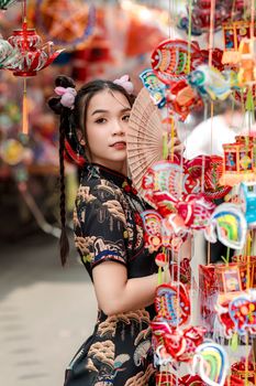 Fashionable woman in traditional dress with fan amidst colorful lanterns in Ho Chi Minh City.