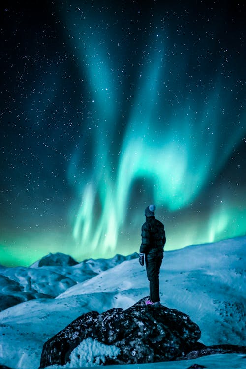 Free Man Standing On A Rock Near Snow Covered Land Stock Photo