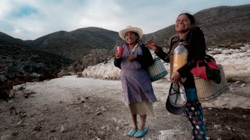 Two women standing in the mountains with bags