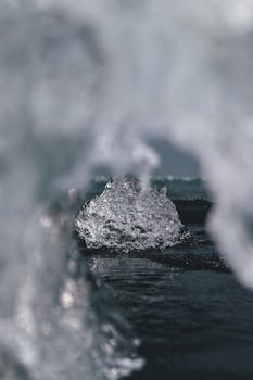 宁静的冬季湖面上结了一层霜冻的冰，挡住了下方清凉的蓝色湖水