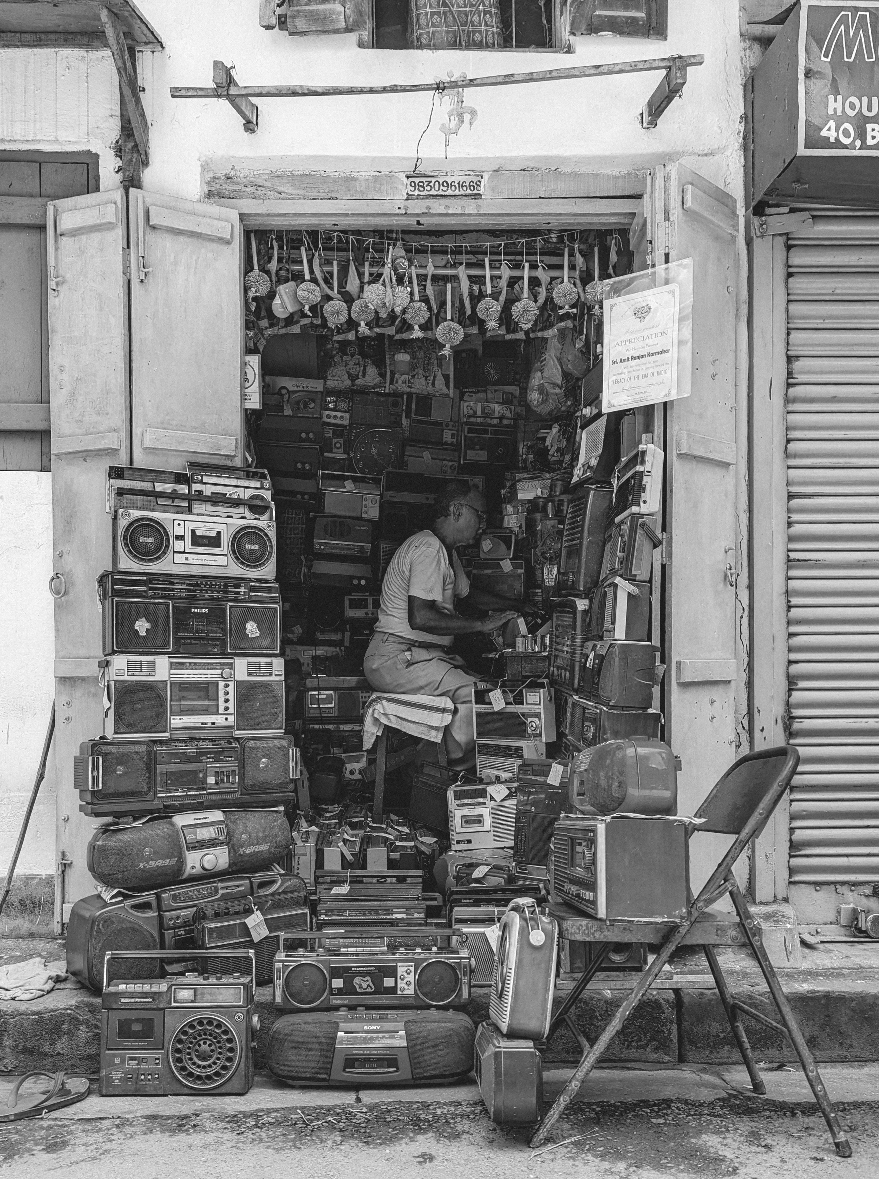 salesman in a small shop selling used old radios and boomboxes