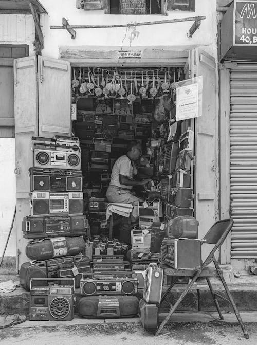 Salesman in a Small Shop Selling Used Old Radios and Boomboxes