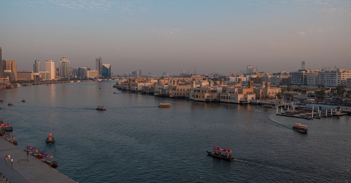 Panoramic view of Dubai Creek's waterfront and skyline at sunset.