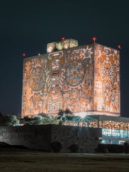 Stunning night view of UNAM library in Mexico City with iconic illuminated murals.