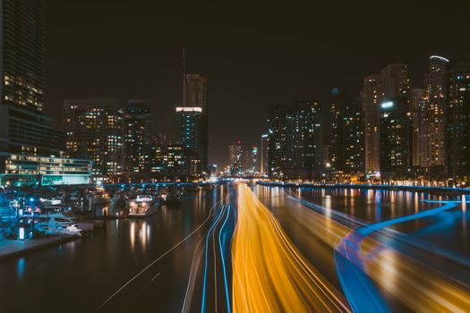 A breathtaking cityscape of Dubai Marina at night, showcasing modern skyscrapers with dynamic light trails over the water.