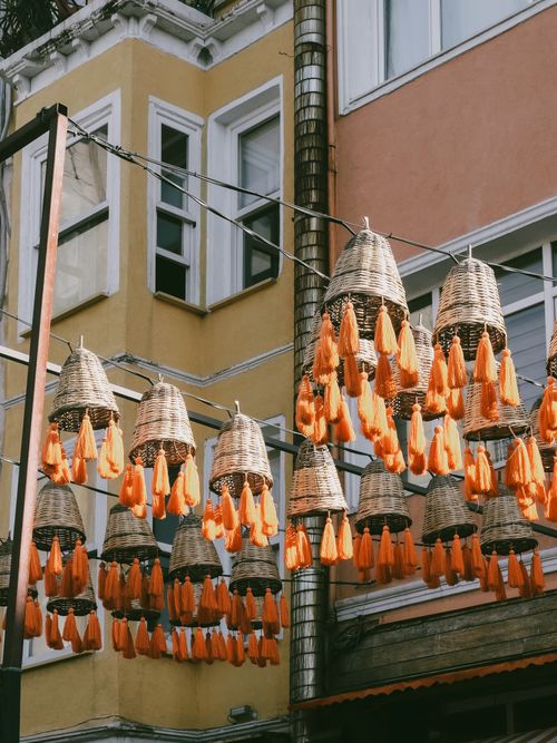 Free Colorful wicker lamps and orange tassels adorn an urban street with historic buildings. Stock Photo