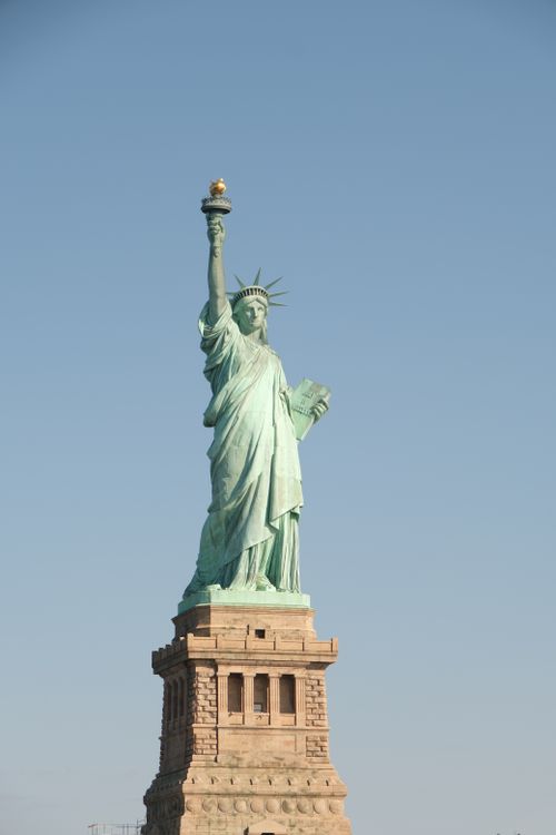 Free The Statue of Liberty stands tall under a bright blue sky, symbolizing freedom. Stock Photo