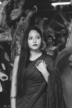 Monochrome portrait of a woman in traditional attire amidst statues, embodying elegance and cultural beauty.