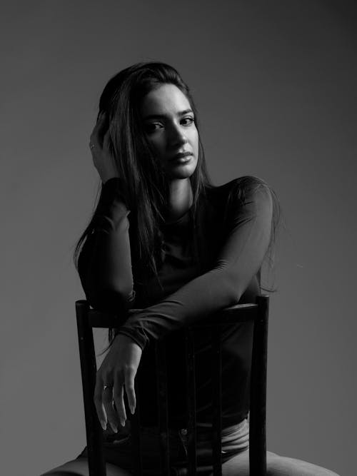 Free Studio Shot of a Young Woman Sitting on a Chair  Stock Photo