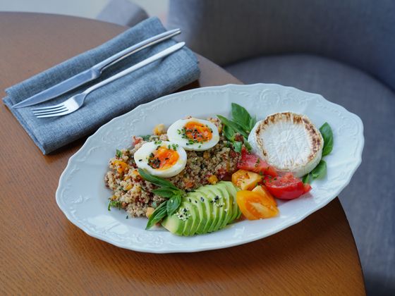 Oval platter with herbed quinoa, soft-boiled eggs, avocado slices, seared goat cheese and tomatoes