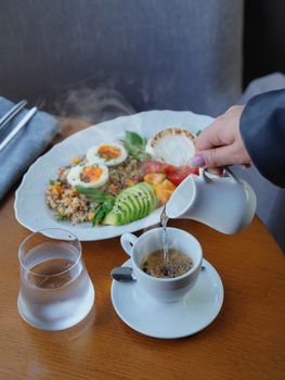 Enjoy a nutritious breakfast with avocado, eggs, and fresh coffee poured hot.