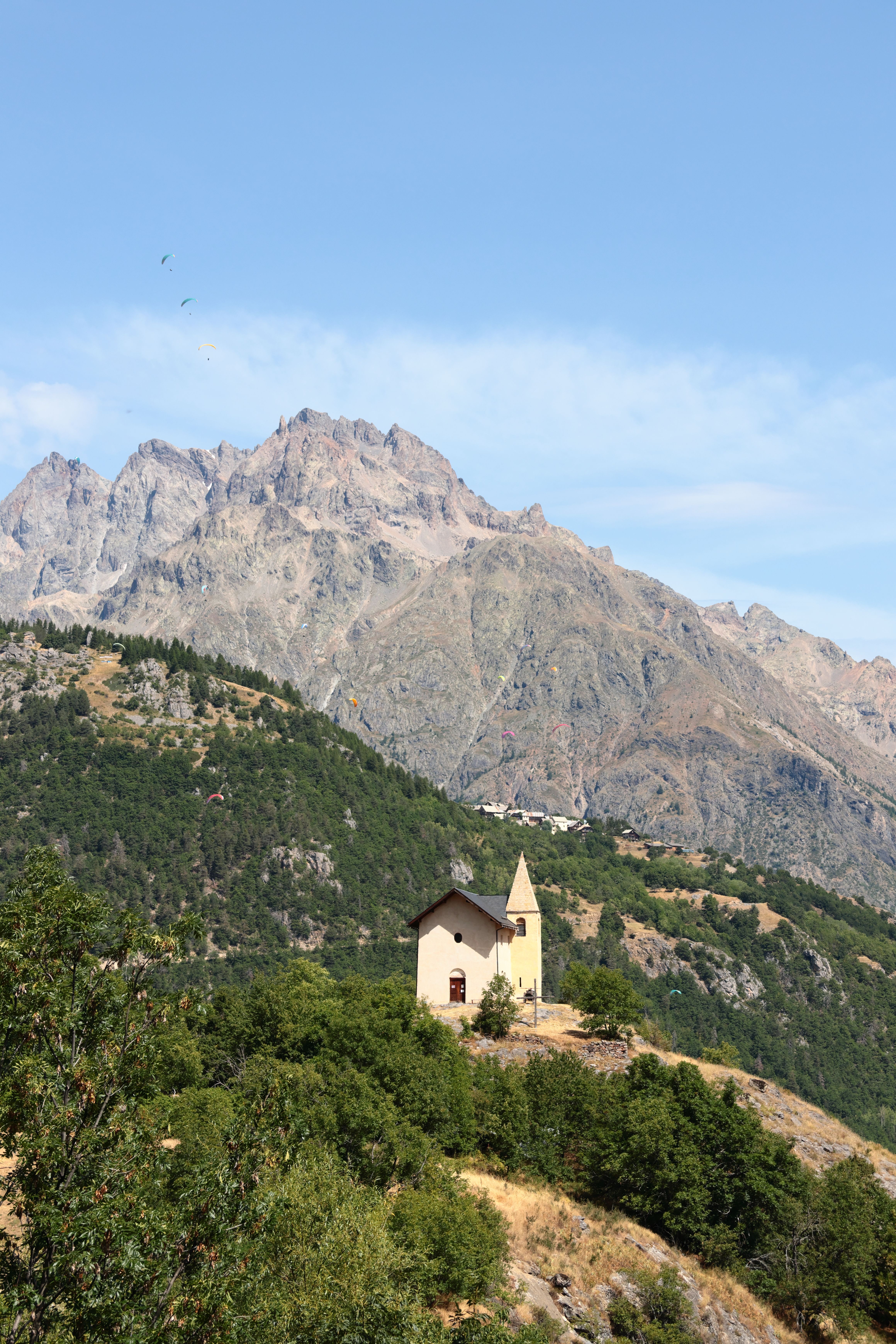 Scenic aerial view of a chapel nestled on a hillside with a mountain backdrop.