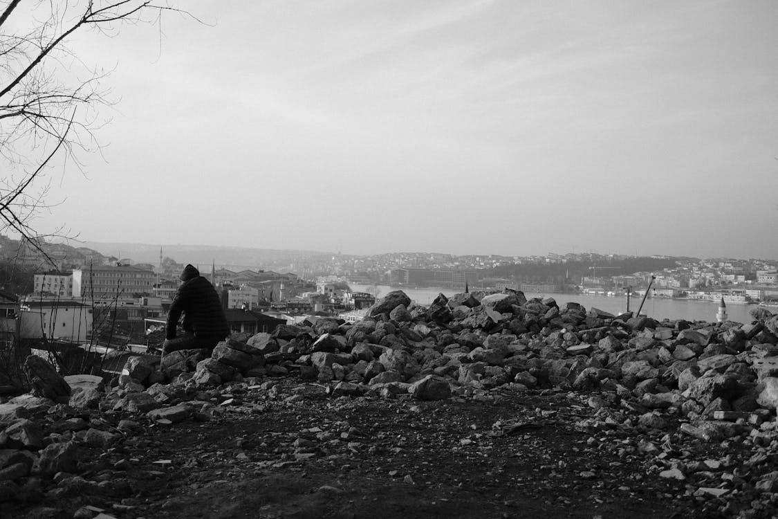 Man Sitting on a Stack of Rocks · Free Stock Photo