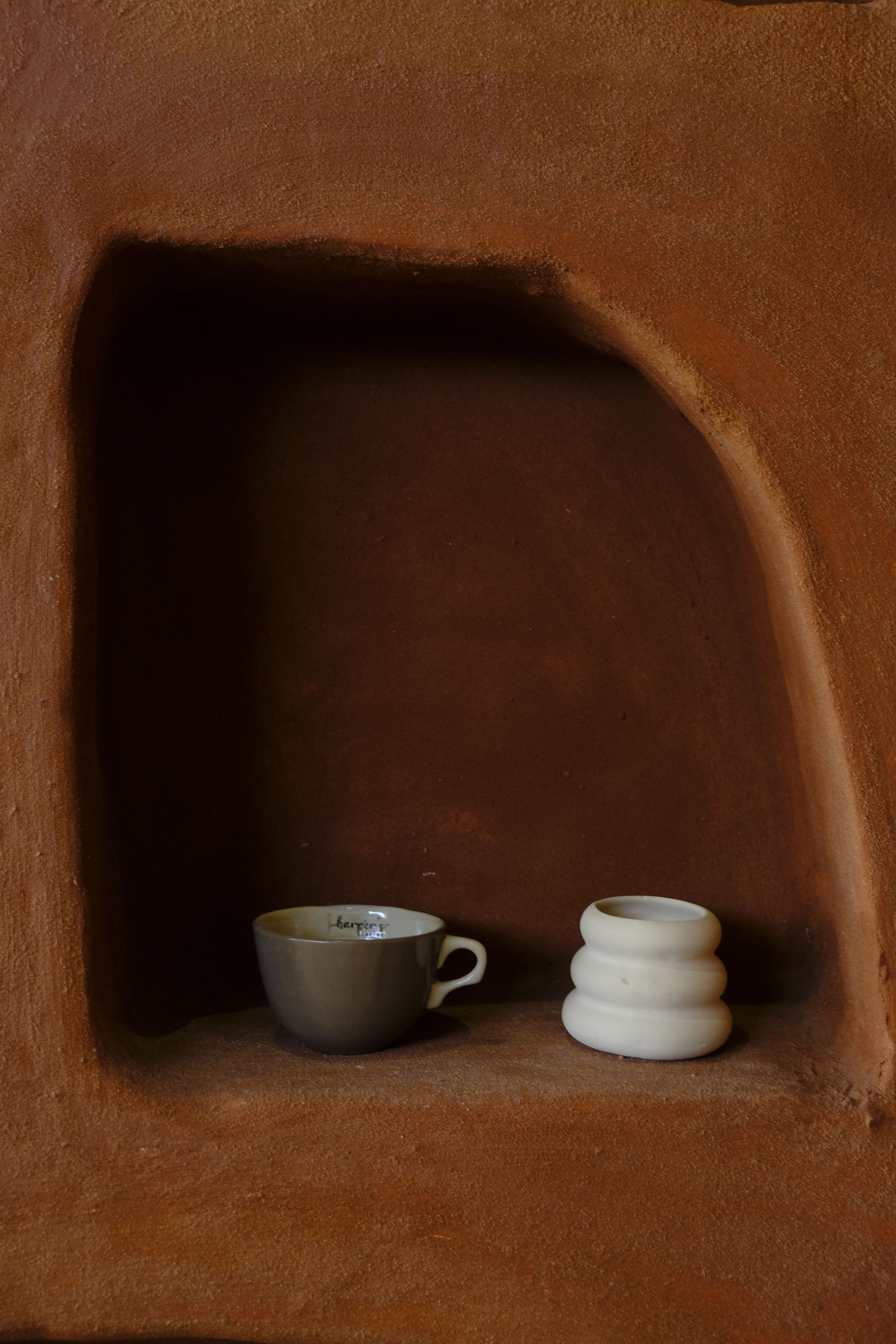Onda carafe and cup set on a pale clay shelf